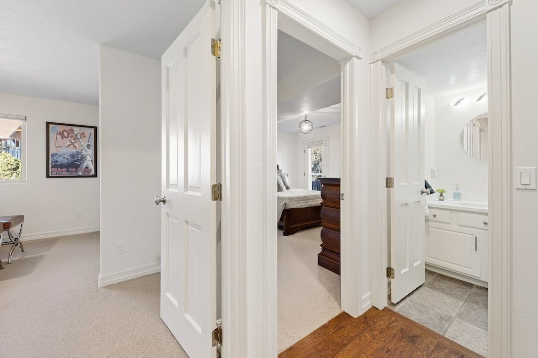 Hallway view into a carpeted bedroom and an adjacent bathroom.