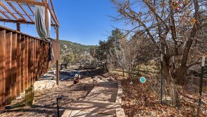 A wooden building with a covered patio area, a pathway, and a fenced garden with trees and shrubs. - Eagle, CO Private Mountain Retreat near Vail (Eagle)