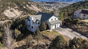 A two-story house with a garage, surrounded by a hilly landscape and sparse vegetation. - Eagle, CO Private Mountain Retreat near Vail (Eagle)