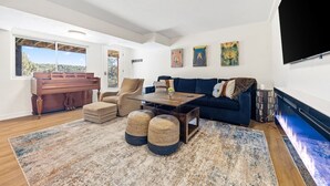 A spacious living room with a piano, a blue couch, and a large TV. - Eagle, CO Private Mountain Retreat near Vail (Eagle)
