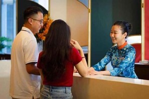 A reception desk with a person seated behind it. - Panorama Nha Trang SanVilla (Nha Trang)