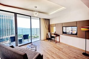 A modern hotel room with a balcony, a sofa, a desk, and a television. - Panorama Nha Trang SanVilla (Nha Trang)