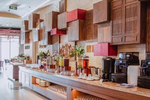 Un espace bar doté d’un long comptoir, de différents distributeurs de boissons et d’une machine à café.