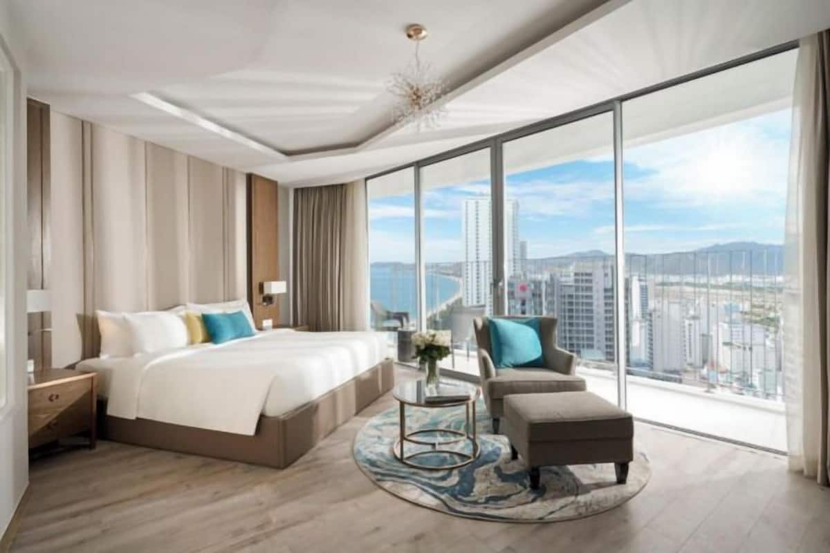 Une chambre d’hôtel moderne dotée d’un grand lit, d’un coin salon et offrant une vue sur la ville.