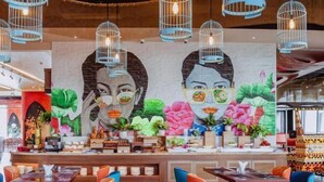 Ein Restaurant mit Wandgemälde, Pendelleuchten und unterschiedlichen Sitzmöglichkeiten.