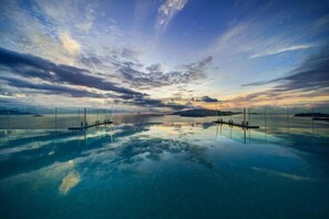 A large, clear pool with a glass floor, surrounded by a glass railing, and a sunset view. - Panorama Nha Trang SanVilla (Nha Trang)