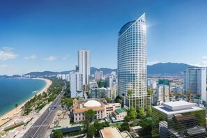 A coastal cityscape with modern high-rise buildings, a beach, and a clear sky. - Panorama Nha Trang SanVilla (Nha Trang)