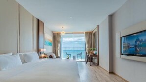 Ein Hotelzimmer mit einem großen Bett, einem Schreibtisch, einem Sessel, einem Fernseher und einem Balkon mit Aussicht.
