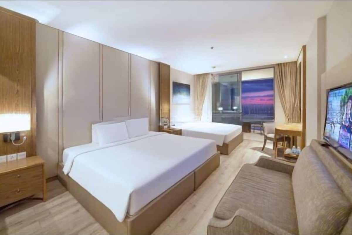 Une chambre d’hôtel avec un grand lit, un canapé, une télévision et un bureau.