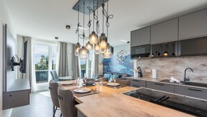 A modern kitchen with a central island, pendant lighting, and a large window. - Luxusapartement mit Meerblick (Nordstrand)