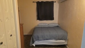 Une chambre à coucher avec un lit, une armoire et un ventilateur de plafond.