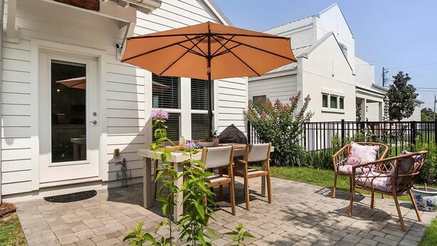 Eine Terrasse mit Tisch, Stühlen, Sonnenschirm und einem kleinen Garten.