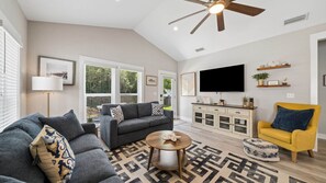 A living room with a sofa, armchair, coffee table, and a TV mounted on the wall. - Sea Breeze Hideaway (Panama City Beach)