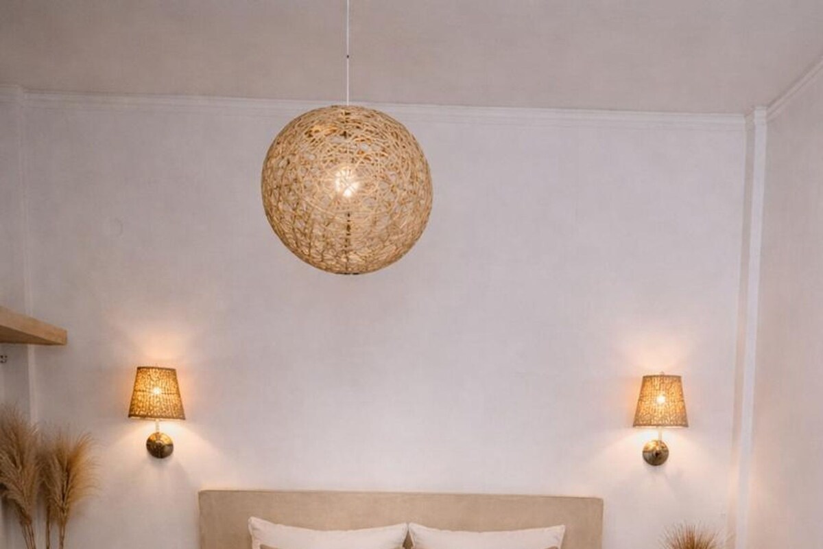 Una camera da letto con un letto grande, due comodini, una lampada a sospensione e un tappeto decorativo.