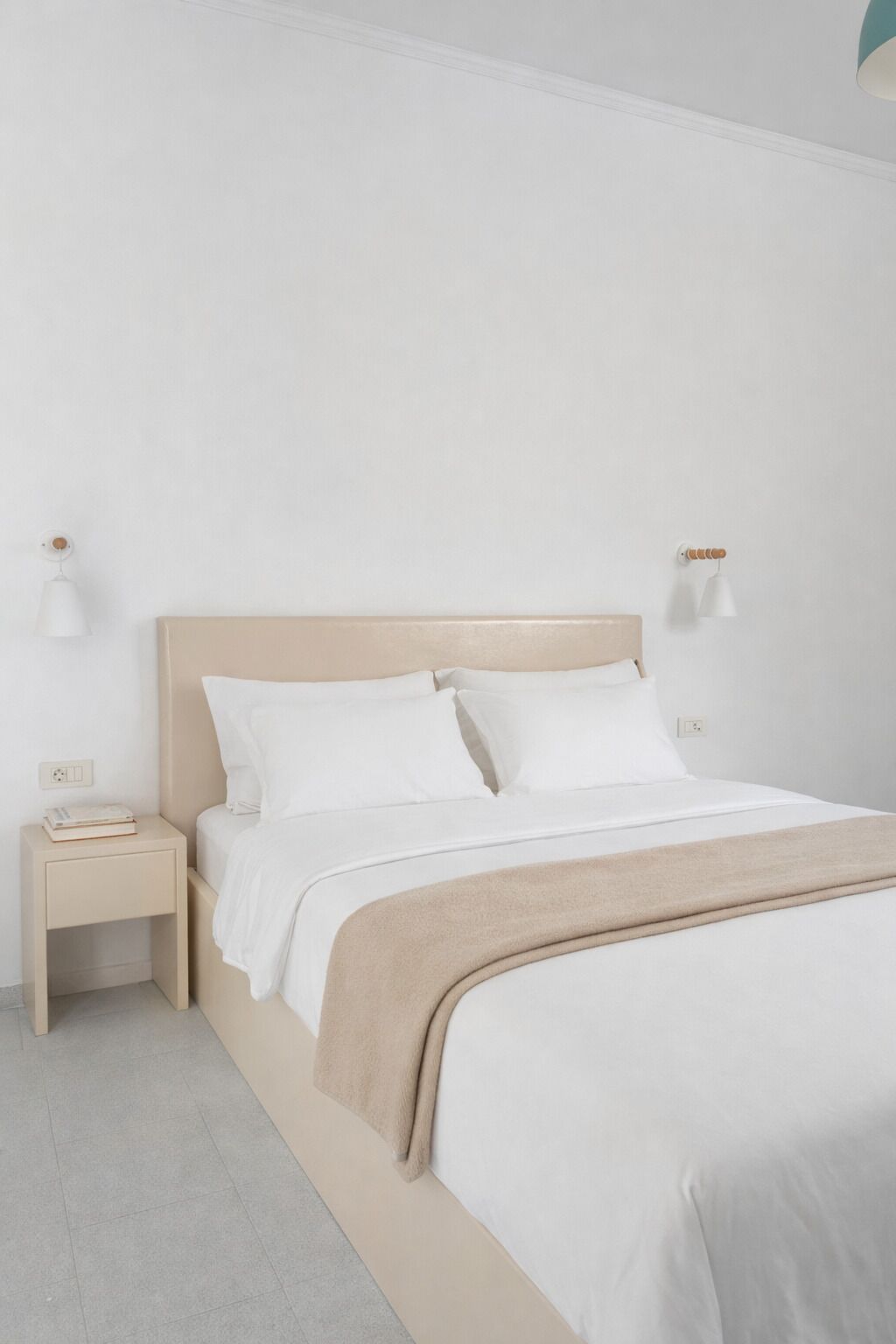 Ein schlicht eingerichtetes Schlafzimmer mit Bett, Nachttischen und Wandlampen.