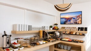 Un'impostazione a buffet con diversi cibi, una macchina per il caffè e un quadro appeso al muro.