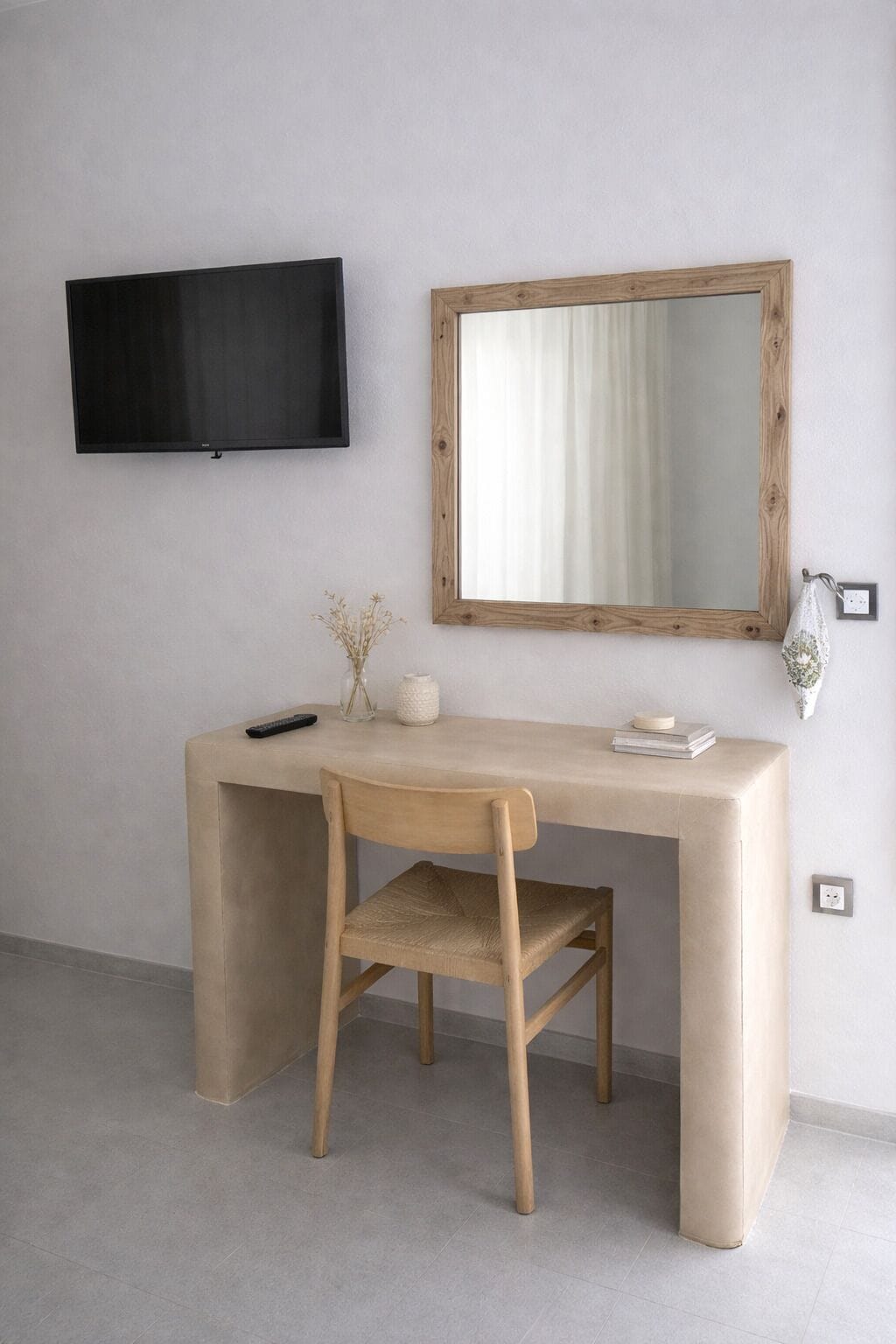 A minimalist room with a desk, chair, TV, and mirror.