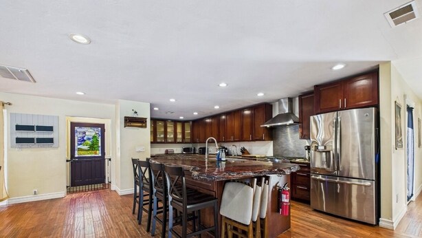 Una cocina moderna con una isla central, electrodomésticos de acero inoxidable y armarios de madera.