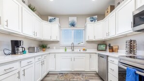 A modern kitchen with white cabinets, a coffee maker, a toaster, and a sink. - Shanah's Vacation Rentals (Ridgecrest)