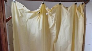 Une salle de bain avec un rideau de douche jaune, des toilettes et un lavabo.