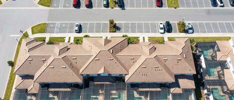 An aerial view of a residential area with multiple houses, a parking lot, and a road.