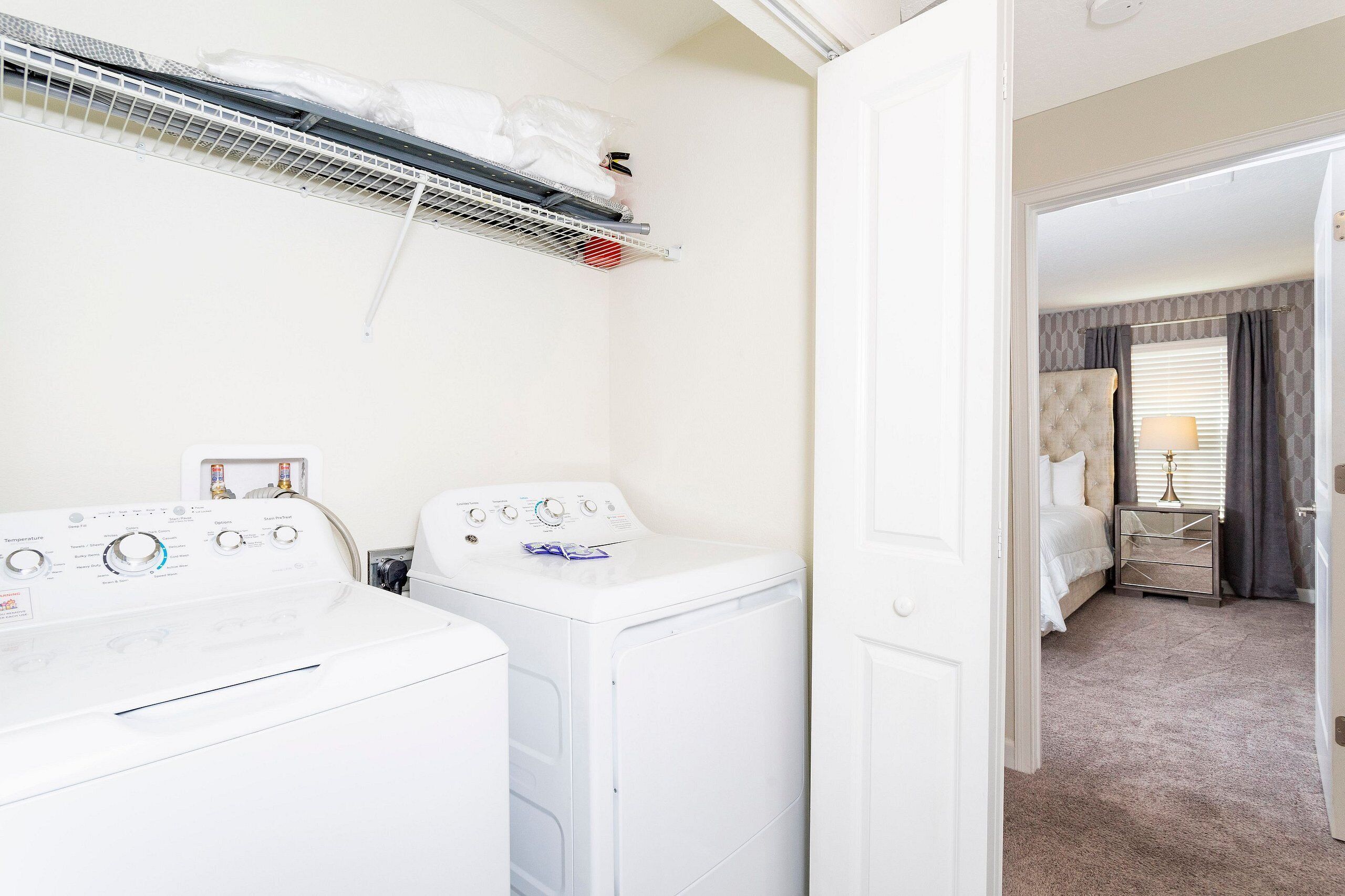 A laundry area with a washing machine, dryer, and a drying rack with clothes.