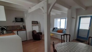 Une cuisine compacte équipée d’un four à micro-ondes, d’un évier et d’un petit réfrigérateur. Un coin salon avec un canapé et une fenêtre avec des stores est également disponible.