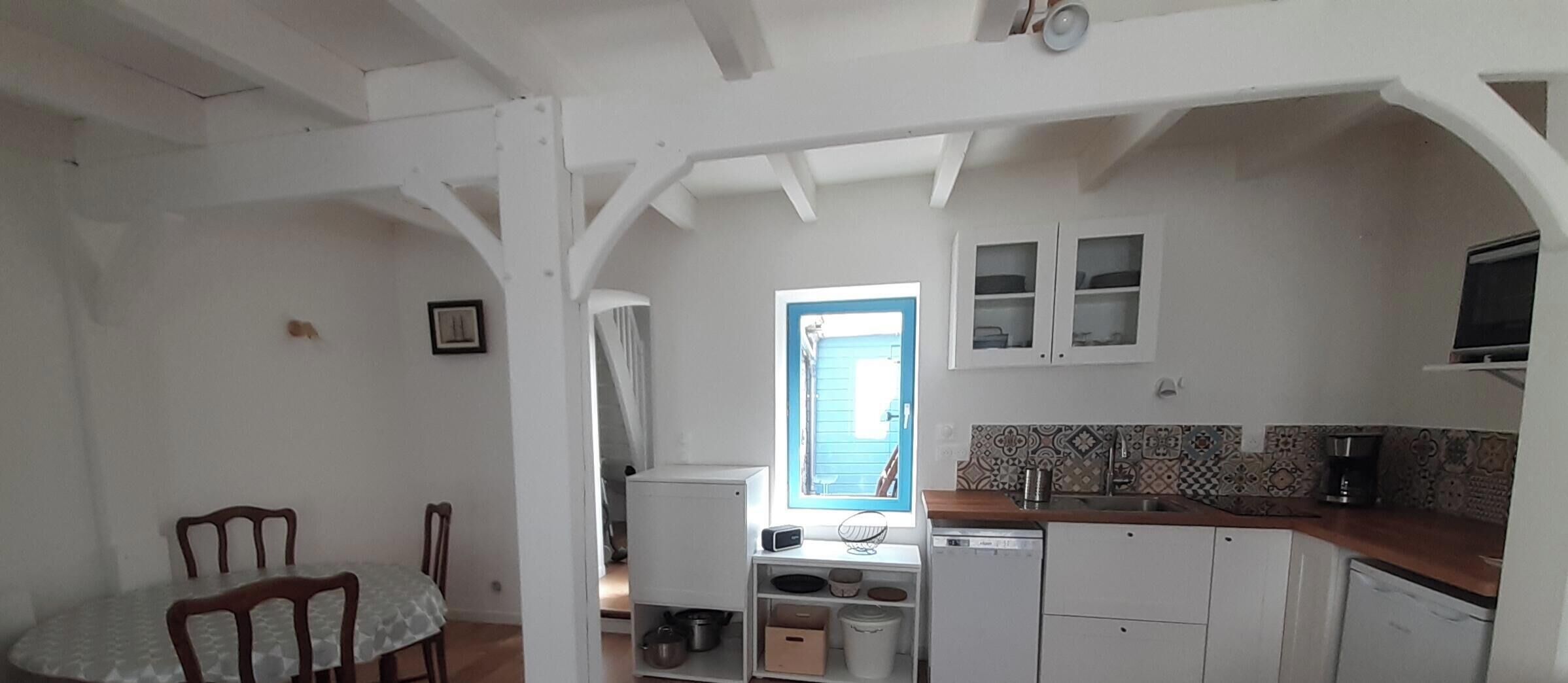 A compact kitchen with white cabinets, a window with a view, and a dining area with a table and chairs.