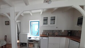Une cuisine compacte avec des meubles blancs, une fenêtre offrant une belle vue et un coin repas comprenant une table et des chaises.