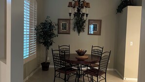 A dining area with a round table, six chairs, a chandelier, and two framed pictures on the wall. - Coastal Comfort in the Heart of Naples (Naples)