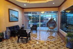 A lobby with a seating area, a hanging chair, and a large window with a view. - Northomes Pensione Bogo By Hiverooms (Bogo City)