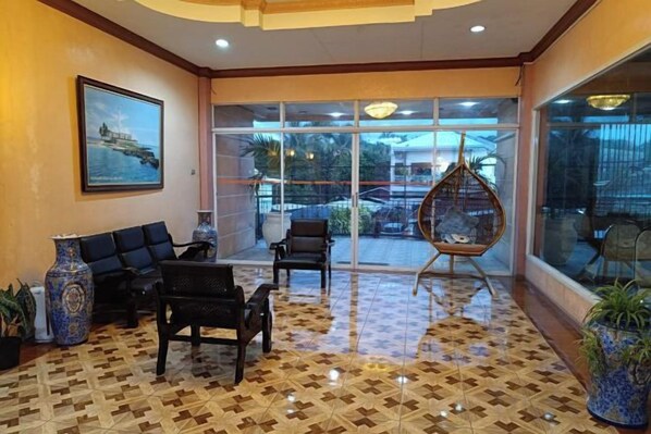 A lobby with a seating area, a hanging chair, and a large window with a view.