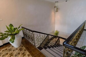 Una escalera con barandilla metálica, una planta en maceta y un suelo con diseño.