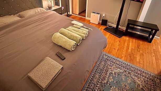 A bedroom with a large bed, a flat-screen TV, a fireplace, and a view of a kitchen. - Fabulous studio apartment with AC in West New York (West New York)