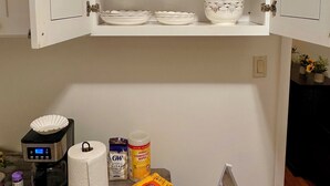 A kitchen with white cabinets, a coffee maker, a roll of paper towels, and a can of disinfectant wipes. - Fabulous studio apartment with AC in West New York (West New York)