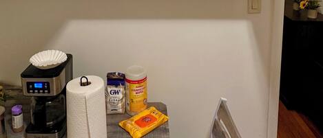 A kitchen with white cabinets, a coffee maker, a roll of paper towels, and a can of disinfectant wipes.