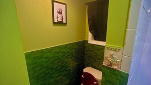 A bathroom with green walls, a toilet, and a framed picture on the wall. - Fabulous studio apartment with AC in West New York (West New York)