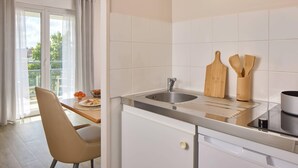 A modern kitchen with a sink, wooden utensils, and a dining area with a chair and table.