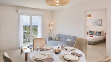 A dining area with a round table set for four, a sofa, and a bed in the background.