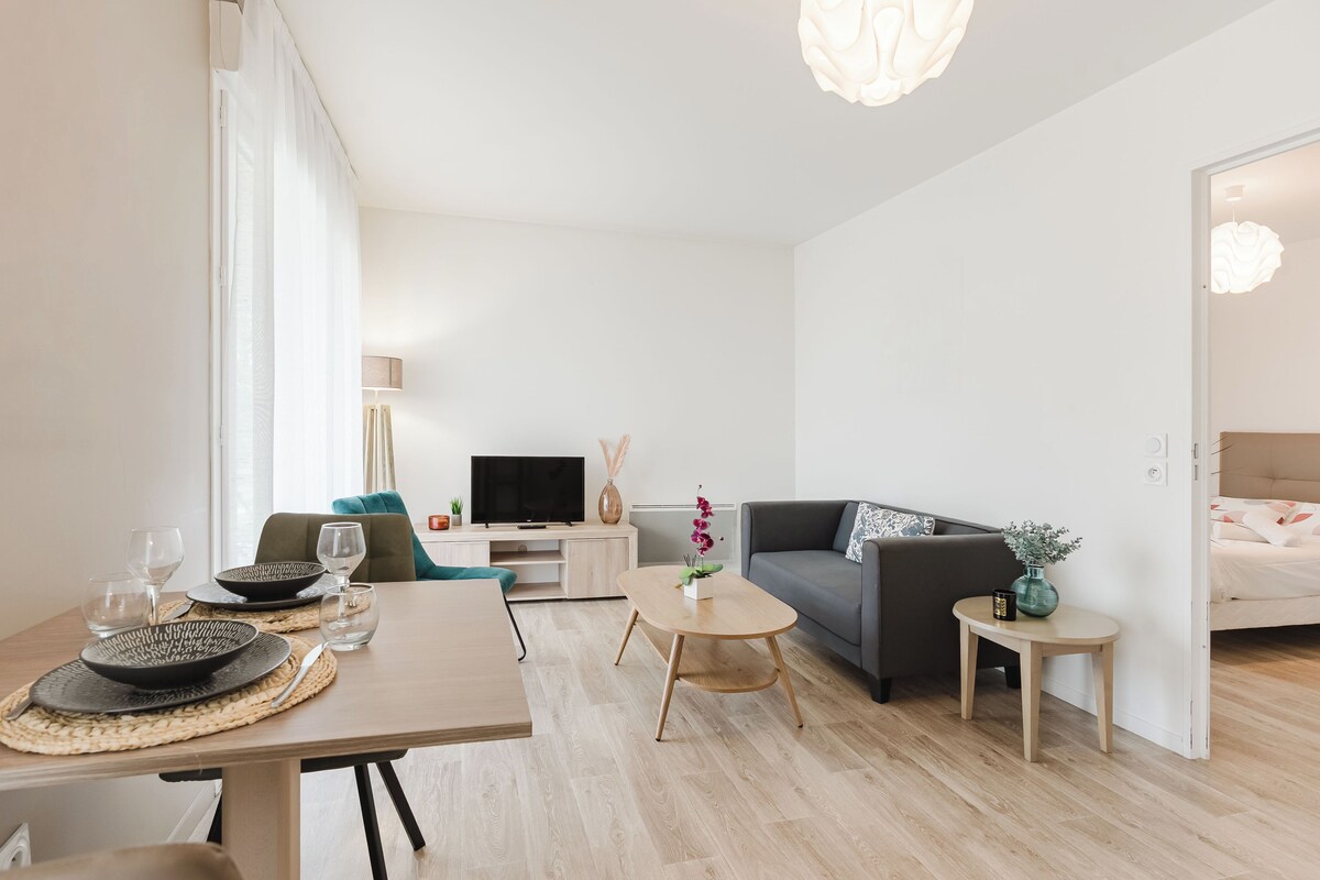 A modern living room with a dining table, sofa, TV, and a small side table.