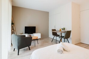 Een moderne hotelkamer met een bed, een bureau, een televisie en een stoel.