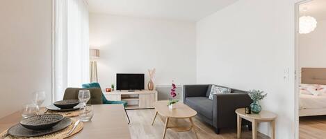A modern living room with a dining table, sofa, and TV.