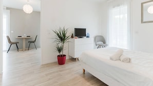 Une chambre d’hôtel moderne équipée d’un lit, d’un bureau avec un ordinateur, d’une chaise et d’une plante en pot.