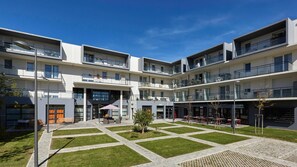 A modern multi-story building with outdoor seating areas and a central courtyard. - Quality Aparthotel Perpignan (Perpignan)