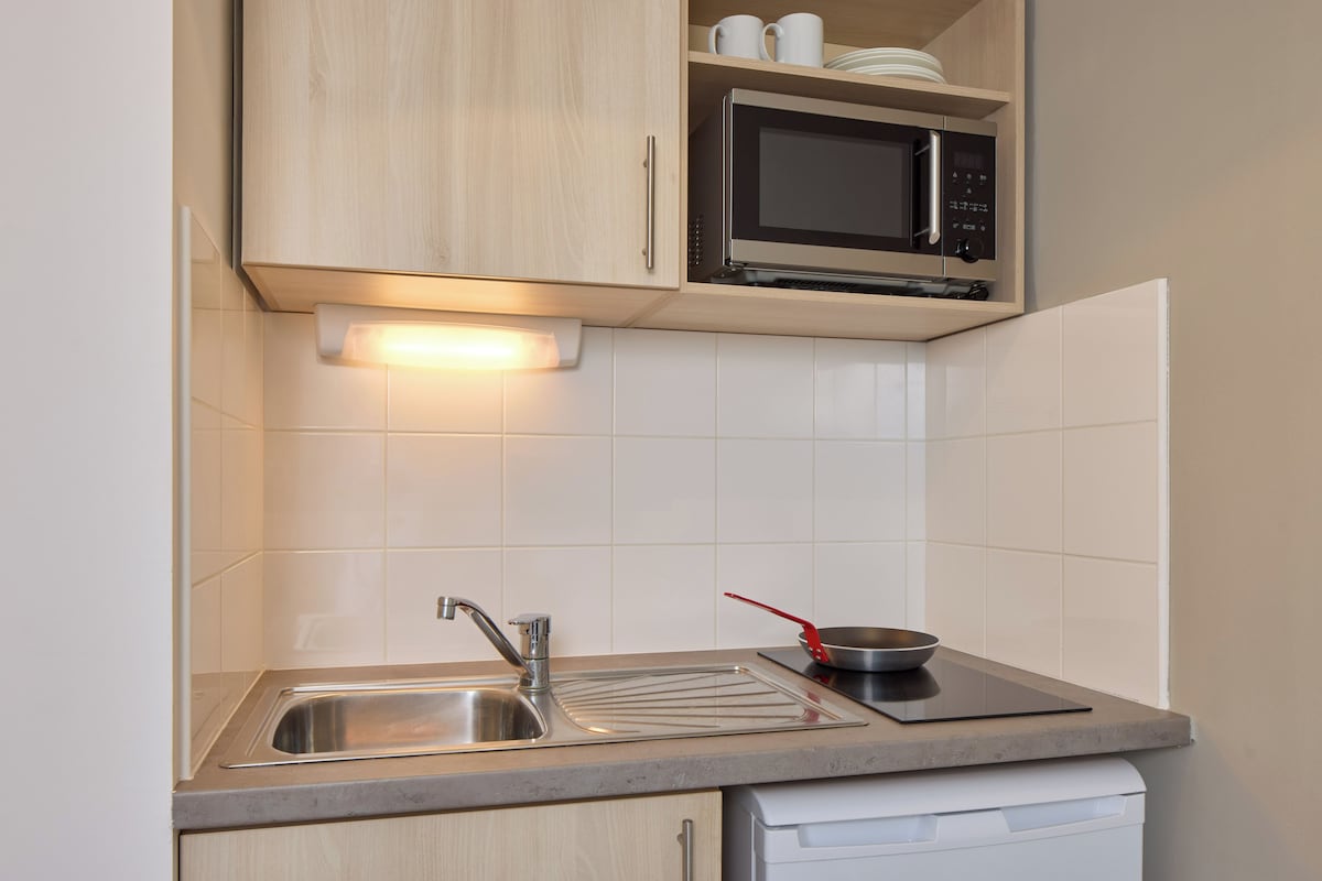 A kitchen with a stainless steel sink, a microwave, and a dish rack.