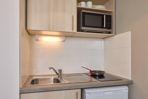 A kitchen with a stainless steel sink, a microwave, and a dish rack. - Quality Aparthotel Perpignan (Perpignan)