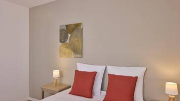 A hotel room with a bed, two nightstands, and a wall art piece.