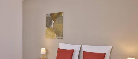A hotel room with a bed, two nightstands, and a wall art piece.