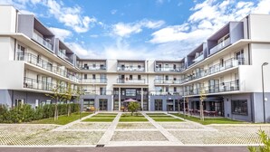 A modern multi-story residential building with balconies, a central courtyard, and a clear sky.