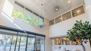 Un interior moderno con ventanas amplias, un ventilador de techo y una planta en maceta.